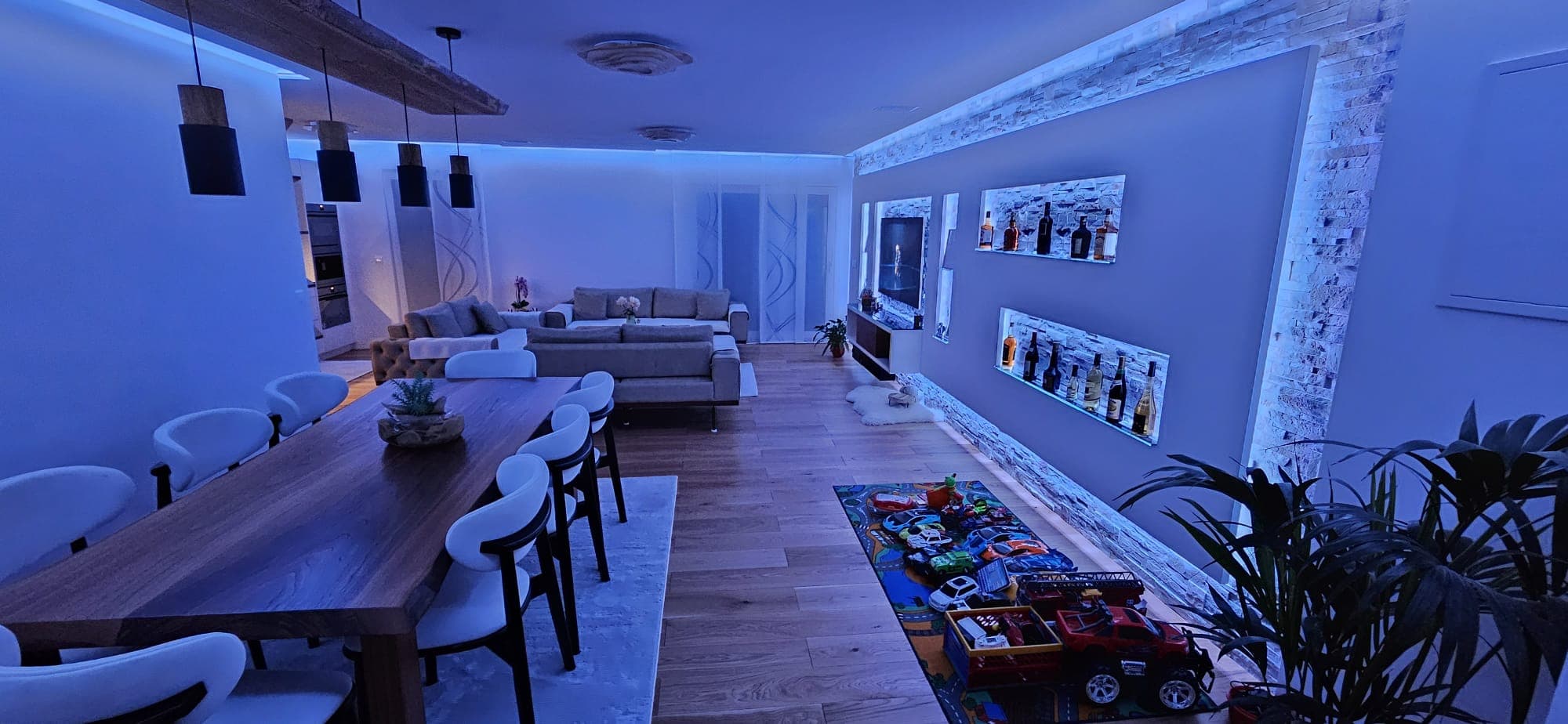 Großzügiges offenes Wohn-Esszimmer mit Massivholz-Esstafel, Naturstein-Akzentwand und blauer Smart-Home-LED, Etrichstraße 41 Top 1 Wien